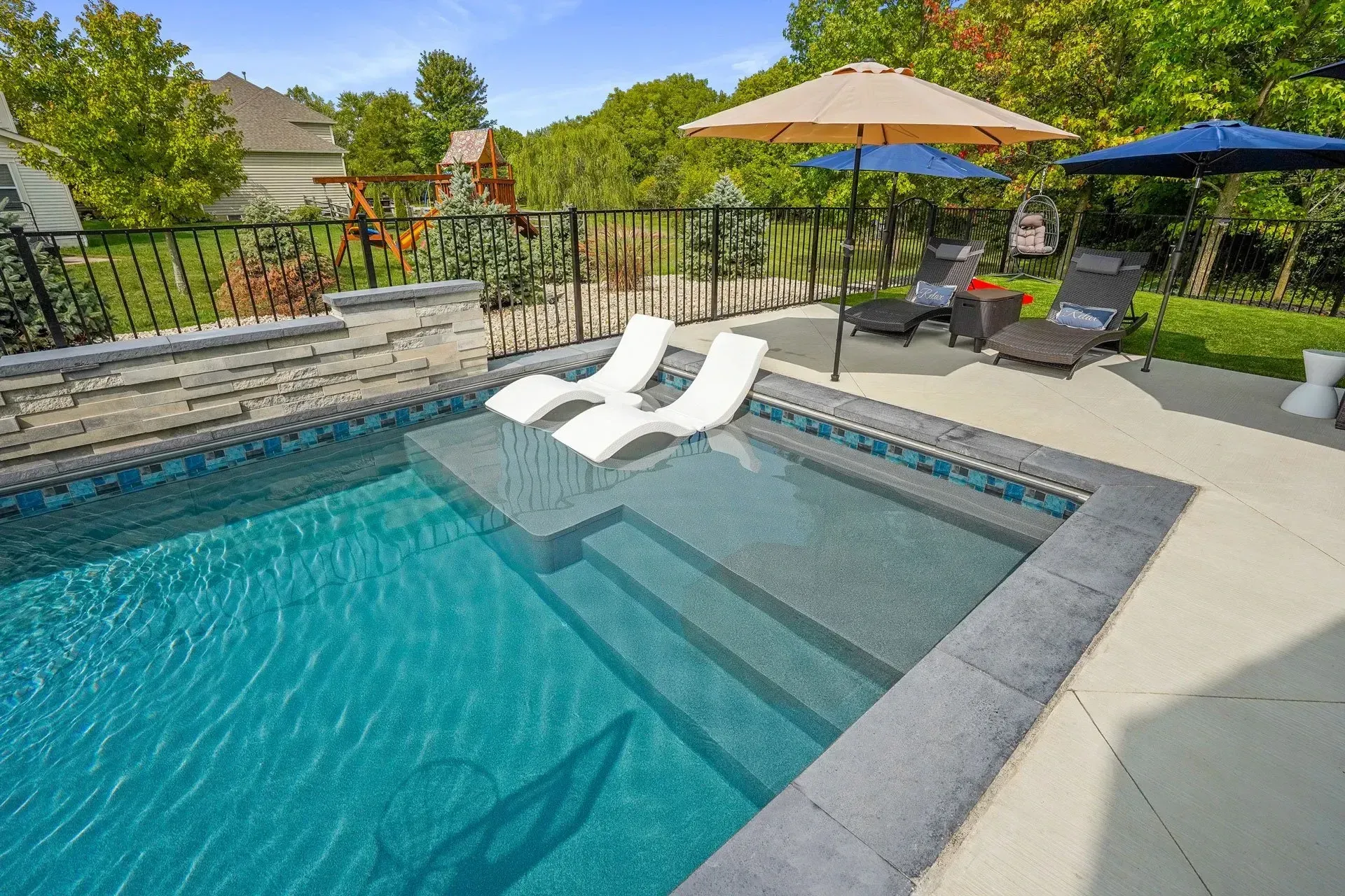 Custom gunite pool with sun ledge and flagstone coping built above engineered retaining wall in Alpharetta, GA