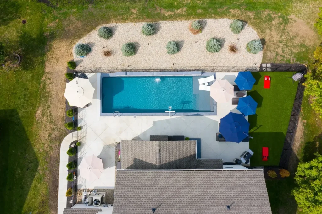 Aerial overhead of small lap-style rectangular pool beside traditional home, with vast gravel-and-boxwood Japanese garden-style landscape — custom pool design and installation in Cumming, GA by Primetime Pools.