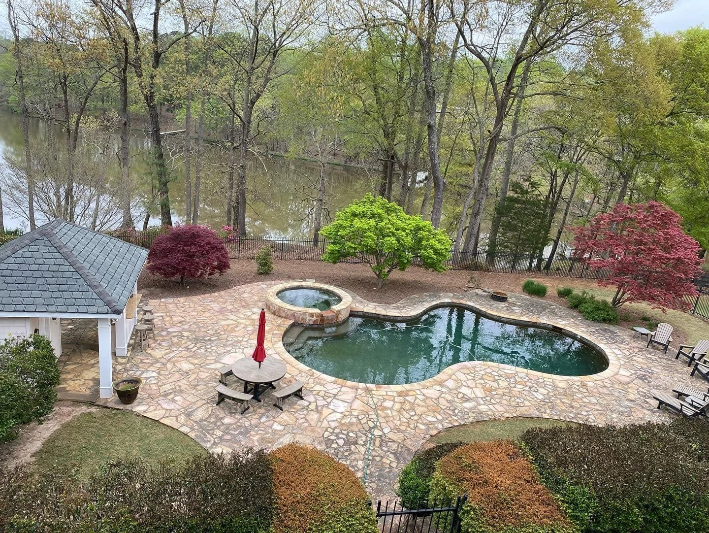 Rectangular gunite pool with raised spa and stone veneer wall built on sloped lot in Dacula, GA