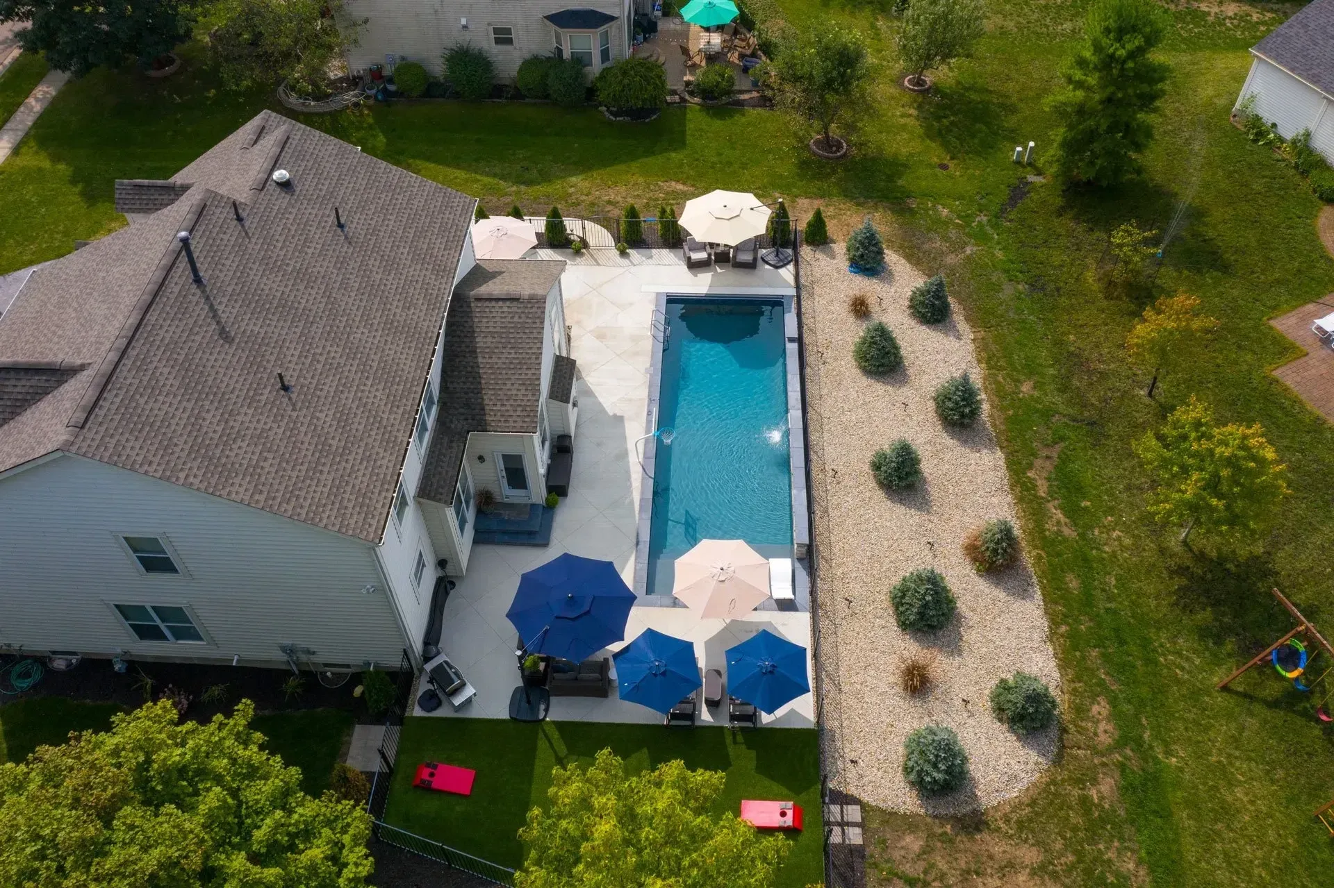 Aerial overhead of narrow rectangular pool with circular spa and gravel landscape beds at Dawsonville, GA home