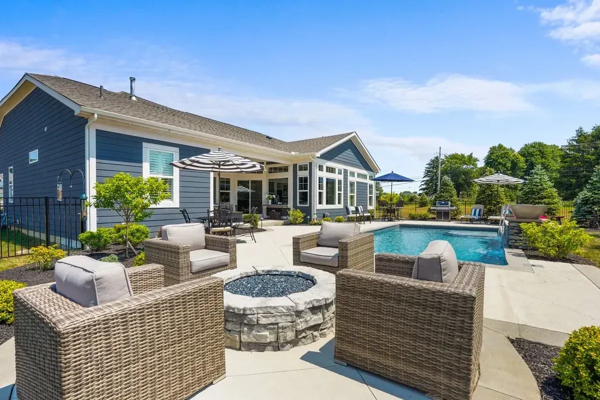 Small rectangular pool with attached spa, round stacked-stone firepit conversation ring, and clipped boxwood mounds in a Marietta, GA suburban backyard