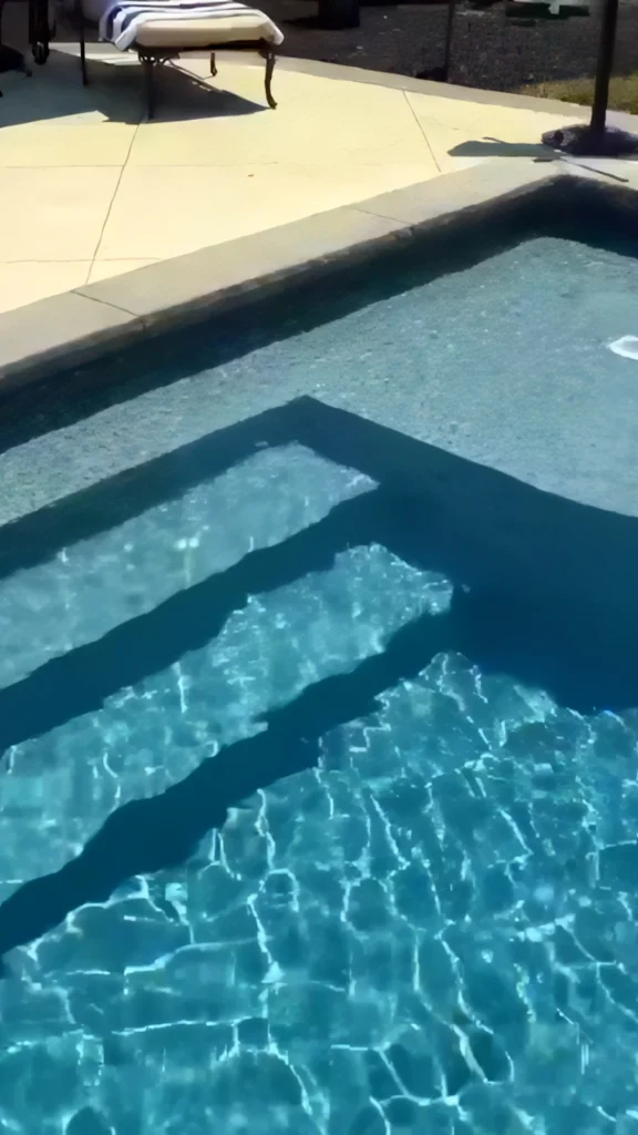 Closeup submerged shot showing pool step detail in clear water, in-pool corner step bench with shadow from striped cushion chaise — custom pool design and installation in Marietta, GA by Primetime Pools.