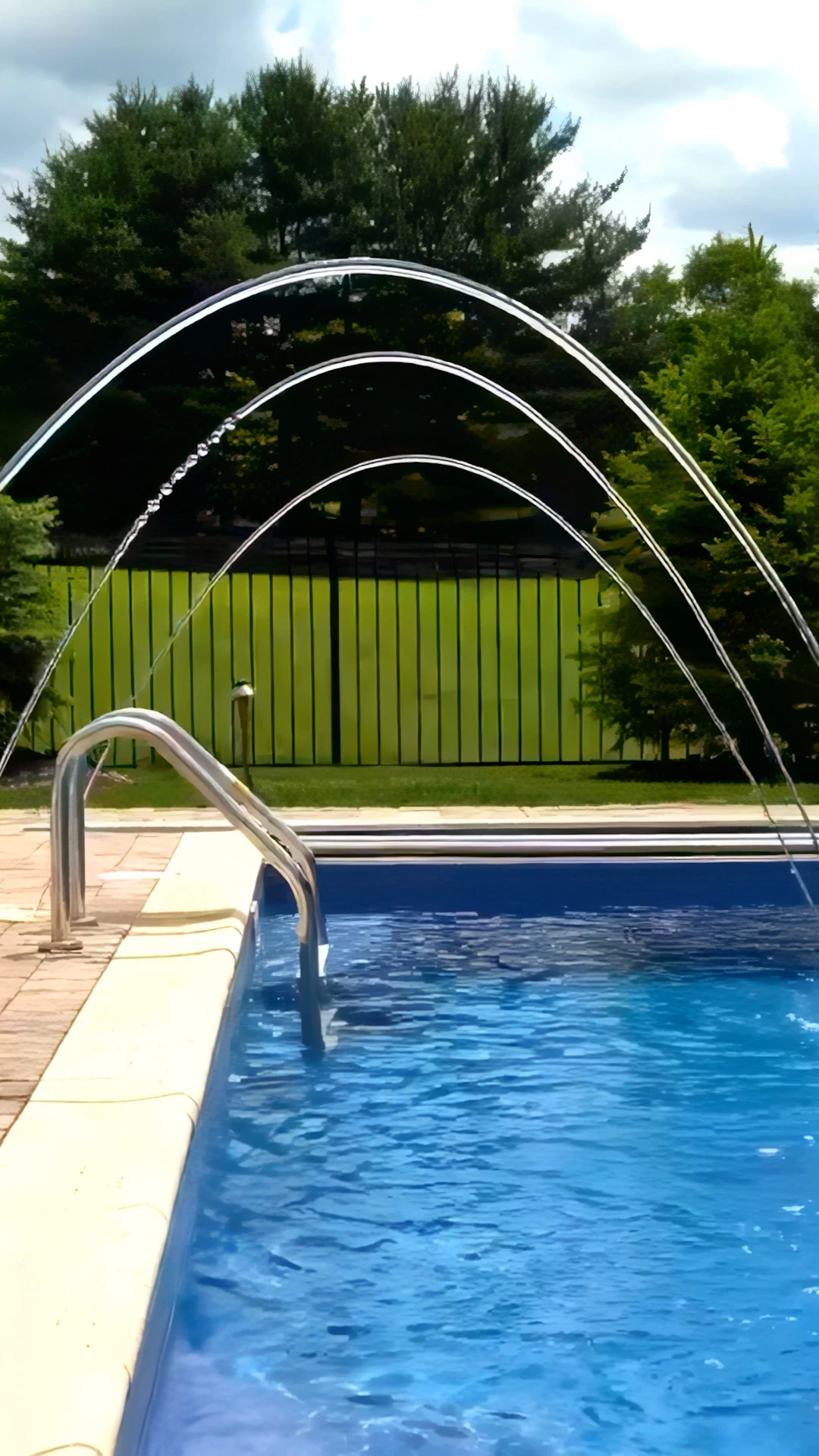 Rectangular pool with laminar deck jets on stainless posts beside outdoor kitchen patio in Marietta, GA