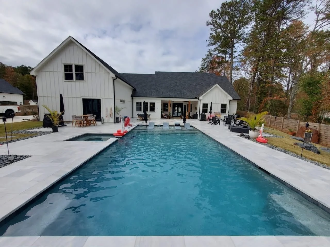 Board-and-batten pavilion with standing-seam Galvalume roof over outdoor kitchen beside finished pool, Milton, GA