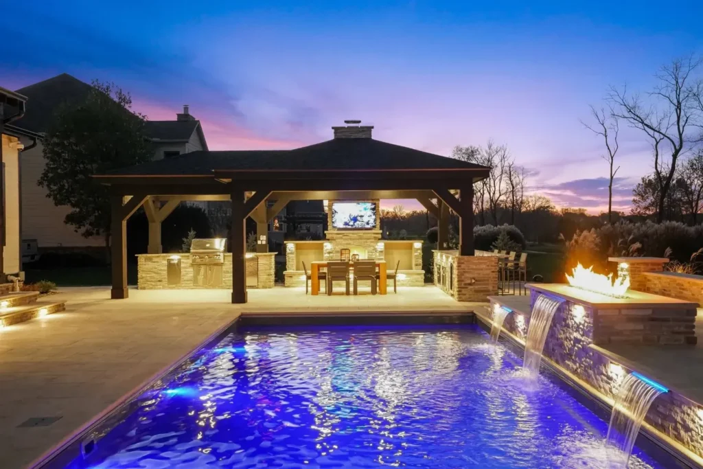 Twilight shot of a rectangular pool with deep blue LED lighting, dual sheer-descent scupper waterfalls, adjacent gas fire feature and… — custom pool lighting in Alpharetta, GA by Primetime Pools.
