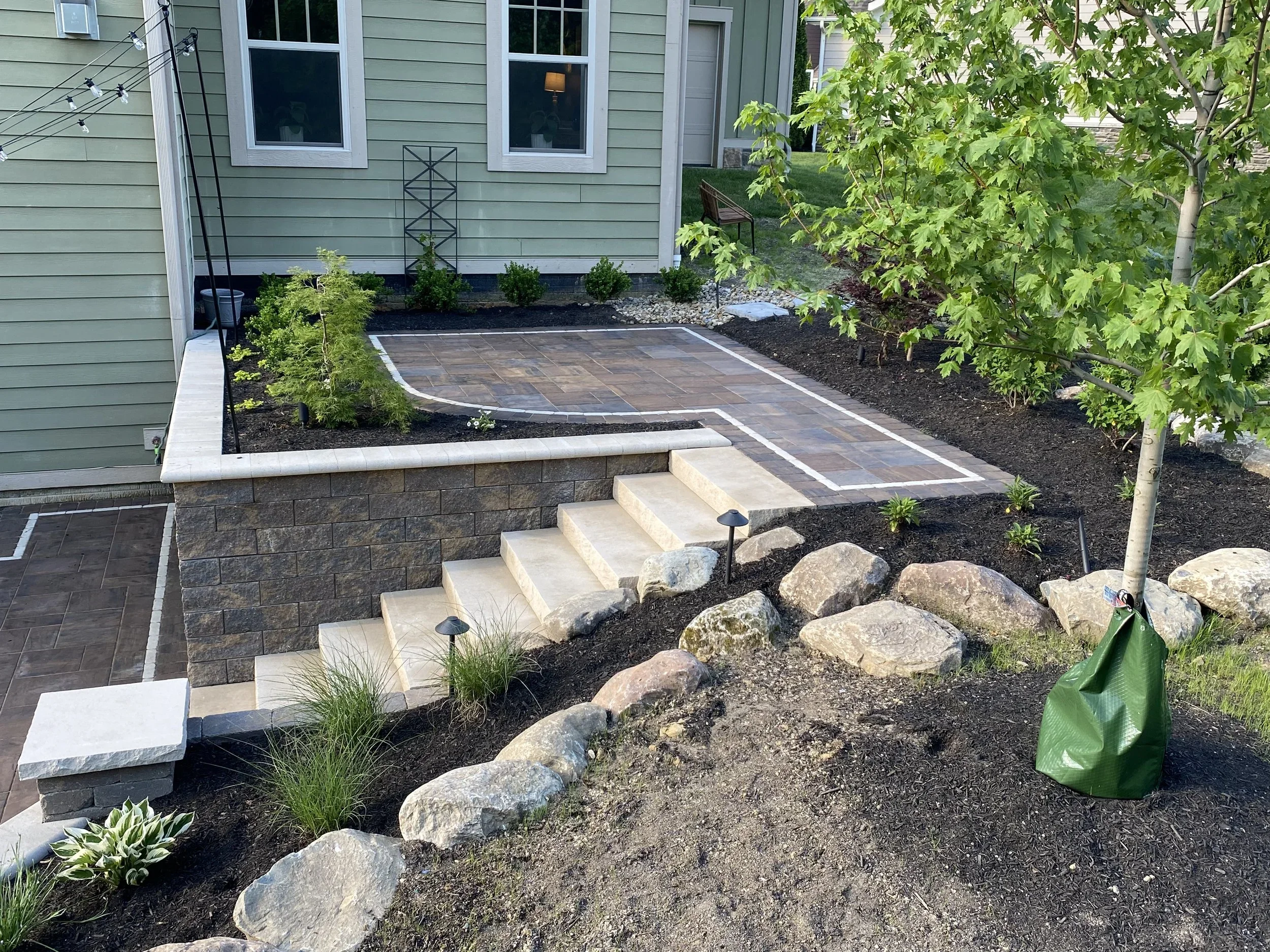 Paver walkway with boulder retaining wall handling grade change on a sloped Dawsonville, GA residential lot