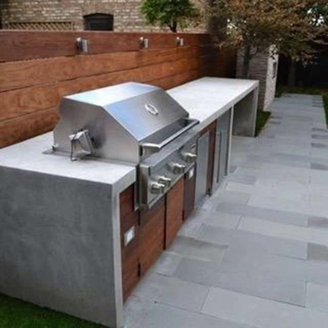 Ultra-modern concrete outdoor kitchen with stainless grill, ipe wood cabinet fronts, and bluestone deck — Dawsonville, GA