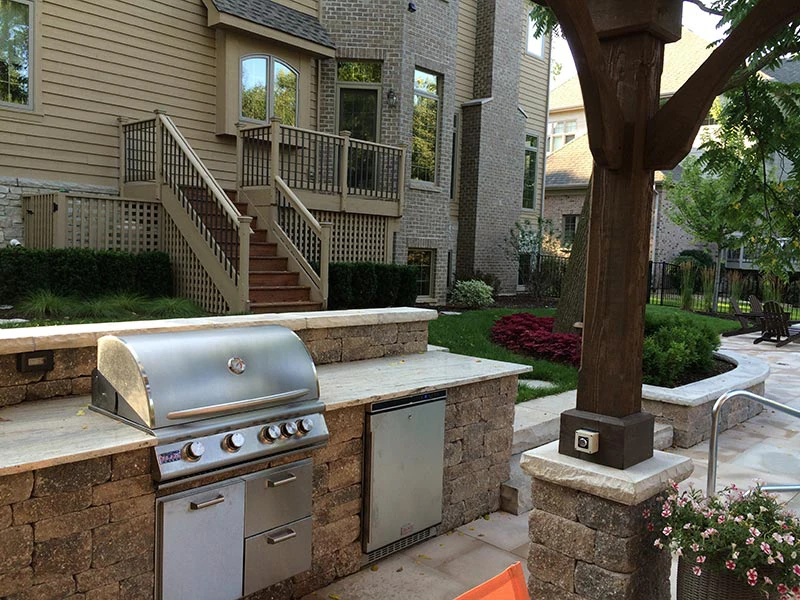 Compact outdoor kitchen with built-in grill and pergola corner post attached to cream siding home in Suwanee, GA
