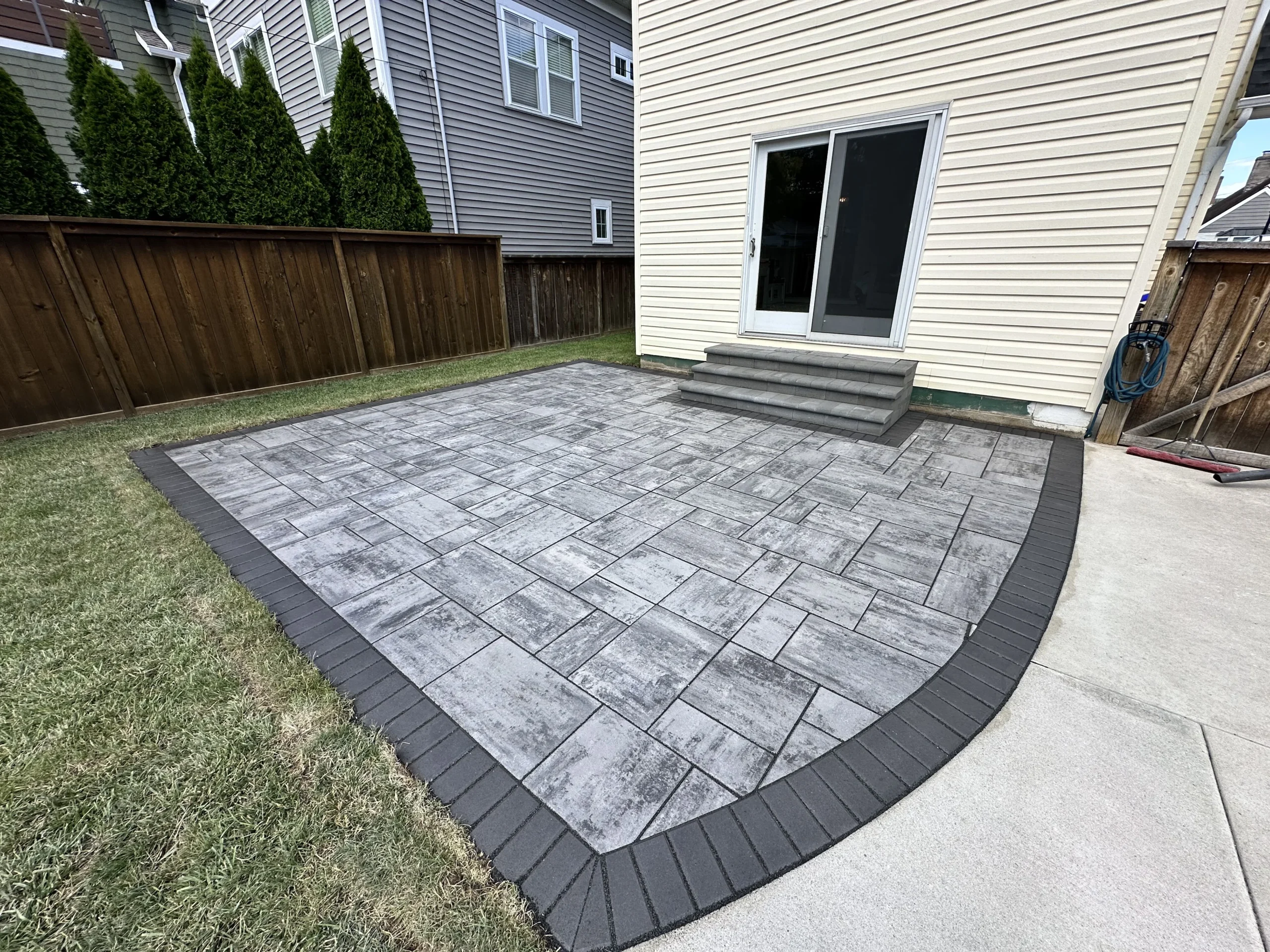 Tumbled paver pool deck in mature landscape with tight joints and clean coping in Alpharetta, GA