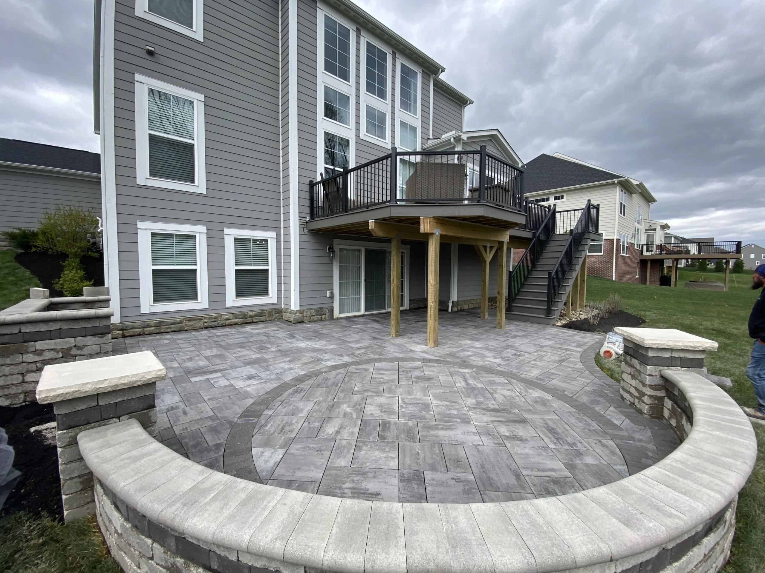 Aerial view of gray paver patio extending from back of Cumming GA home with small round sub-pad in yard
