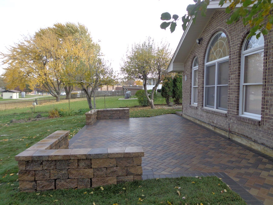 Tumbled tan-chestnut Belgard Holland Stone back patio with stepped seat wall on a red-brick Cumming, GA home