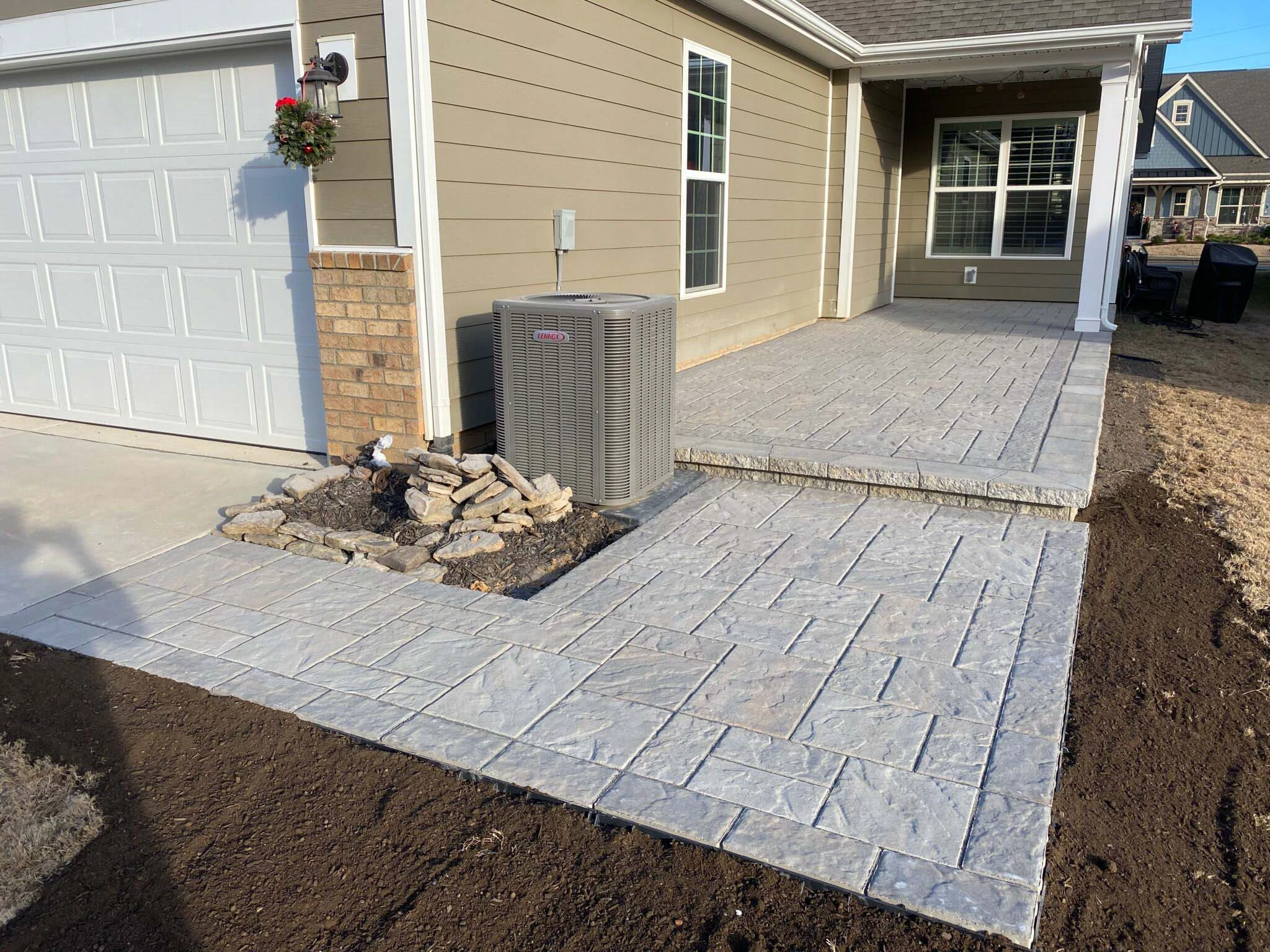 Dacula, GA paver installation crew sweeping polymeric sand into dry joints before first activation pass