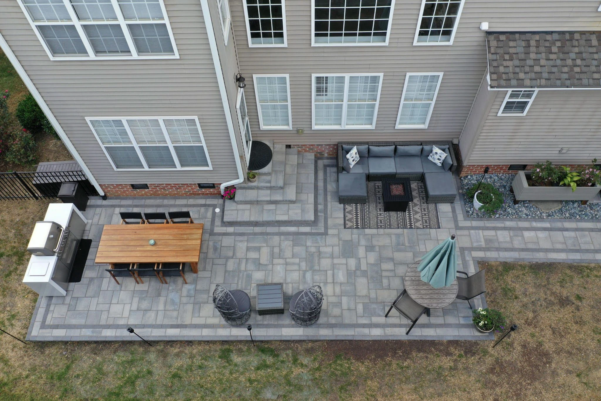Drone overhead of long linear gray paver patio at a two-story home in Suwanee, GA
