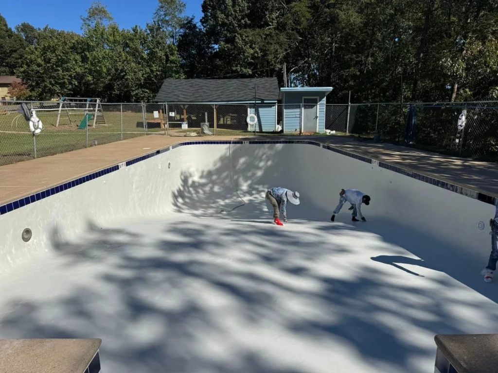 Crew resurfacing a rectangular in-ground pool with fresh white plaster on a sunny autumn day — Primetime Pools crew at work in Dacula, GA by Primetime Pools.