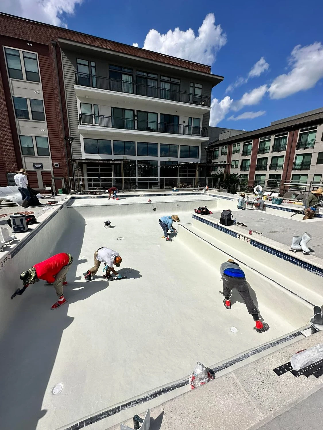 Five-member Primetime Pools crew troweling fresh plaster in a commercial pool resurface in Forsyth County, GA