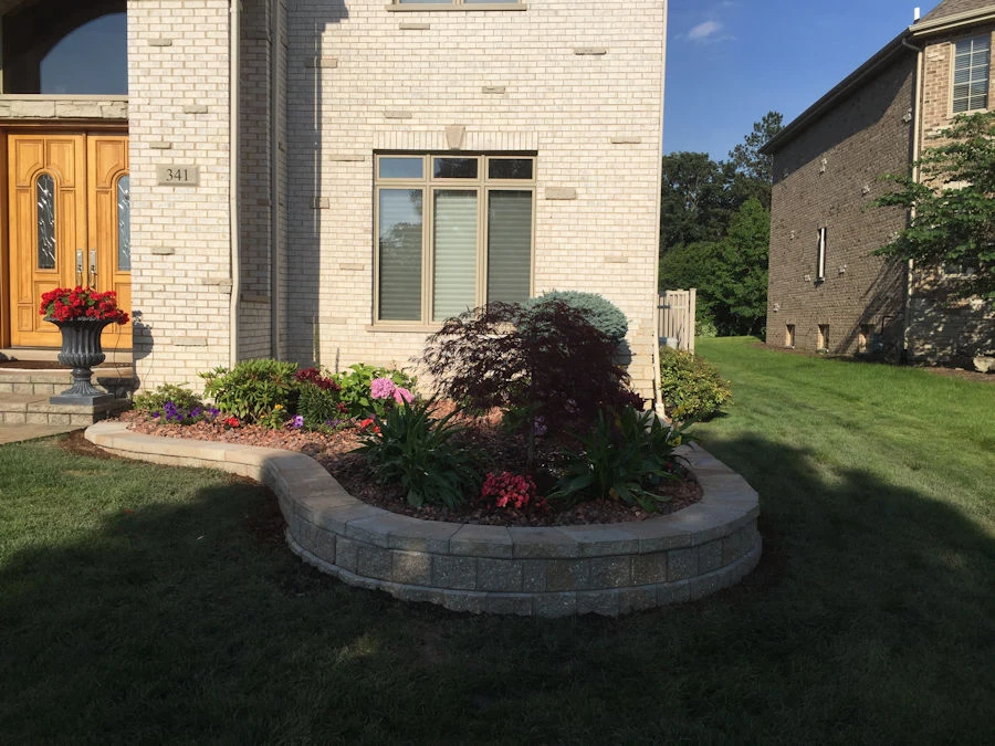 Multi-tier segmental block retaining wall with planting ledge in a Cumming HOA backyard with pool above.