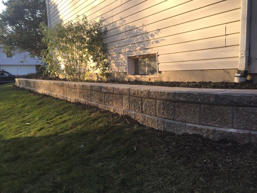 Curved tumbled block retaining wall with integrated planting ledge in a Cumming, GA pool backyard.