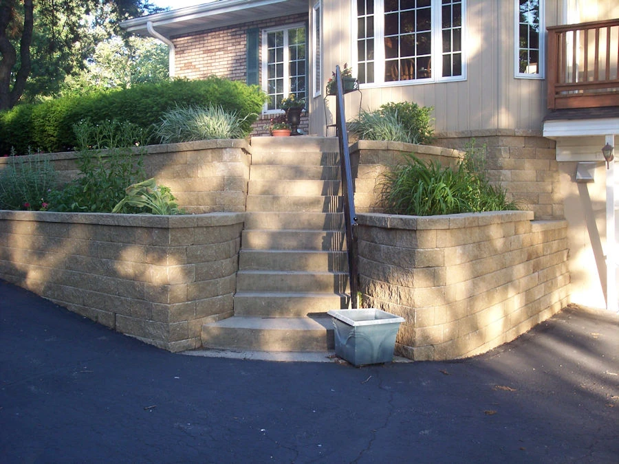 Curved cream-tan segmental-block raised front-entry planter wall with flagstone step pads and perennial plantings, Forsyth County, GA