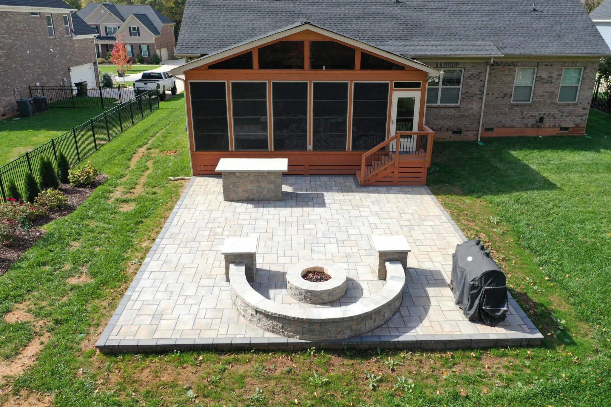 Double-sided stacked stone fireplace with cast stone cap separating a screened porch from an open patio in Cumming, GA
