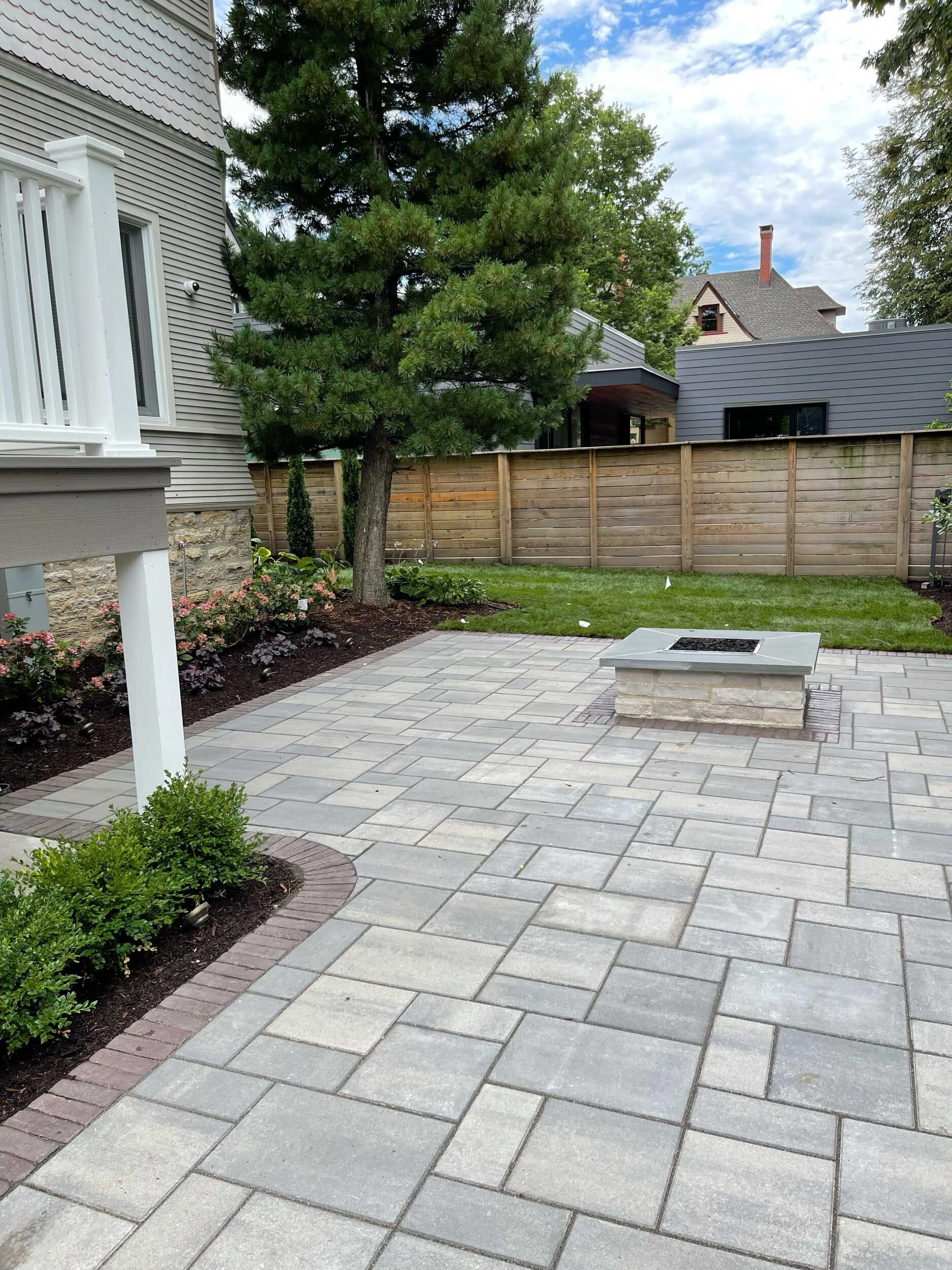 Outdoor fireplace with chimney integrated into a raised patio on a sloped Cumming GA backyard, showing structural fill and drainage management
