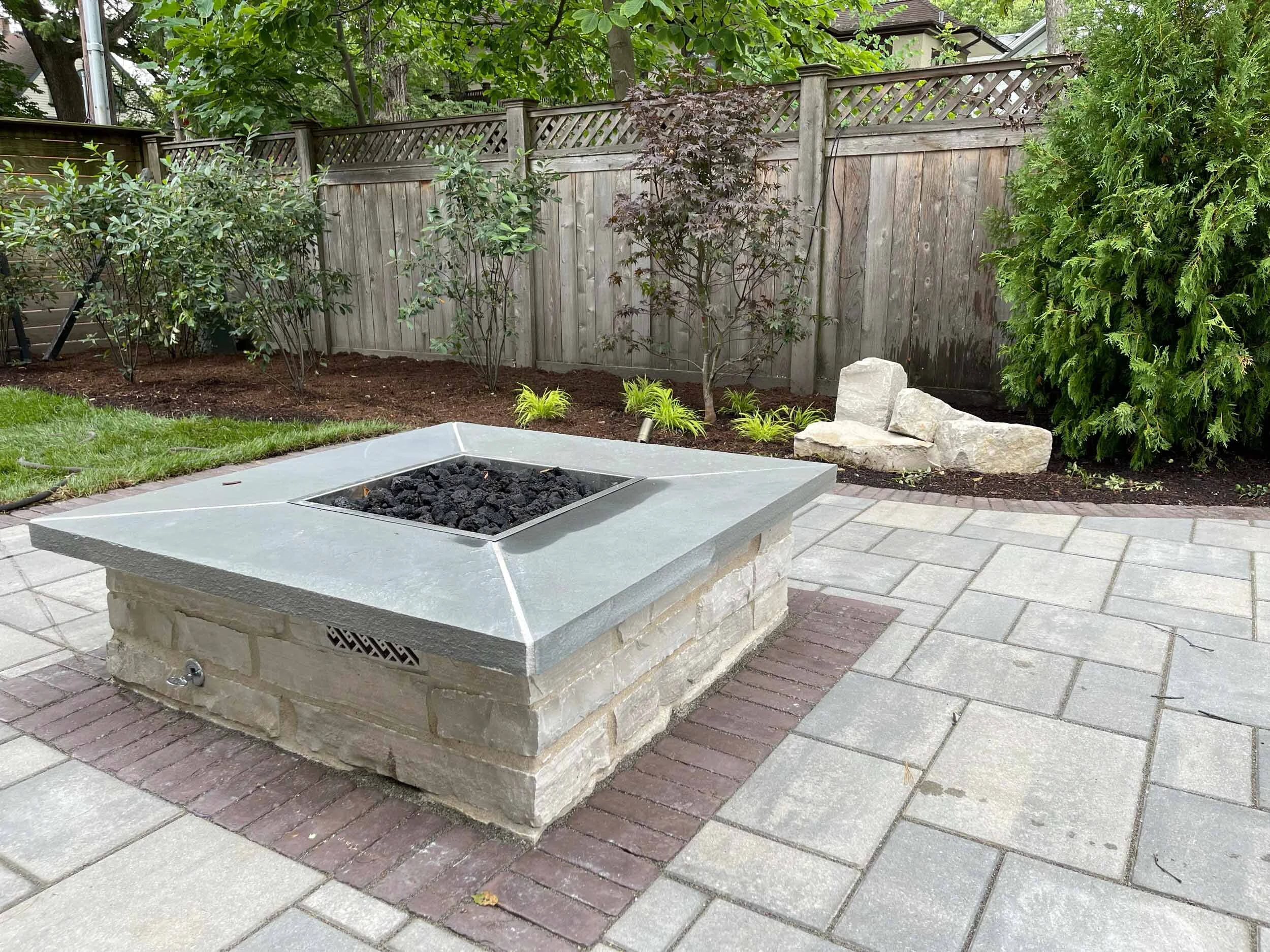 Gas firepit with fire glass burning at dusk on a paver patio in Dacula, GA