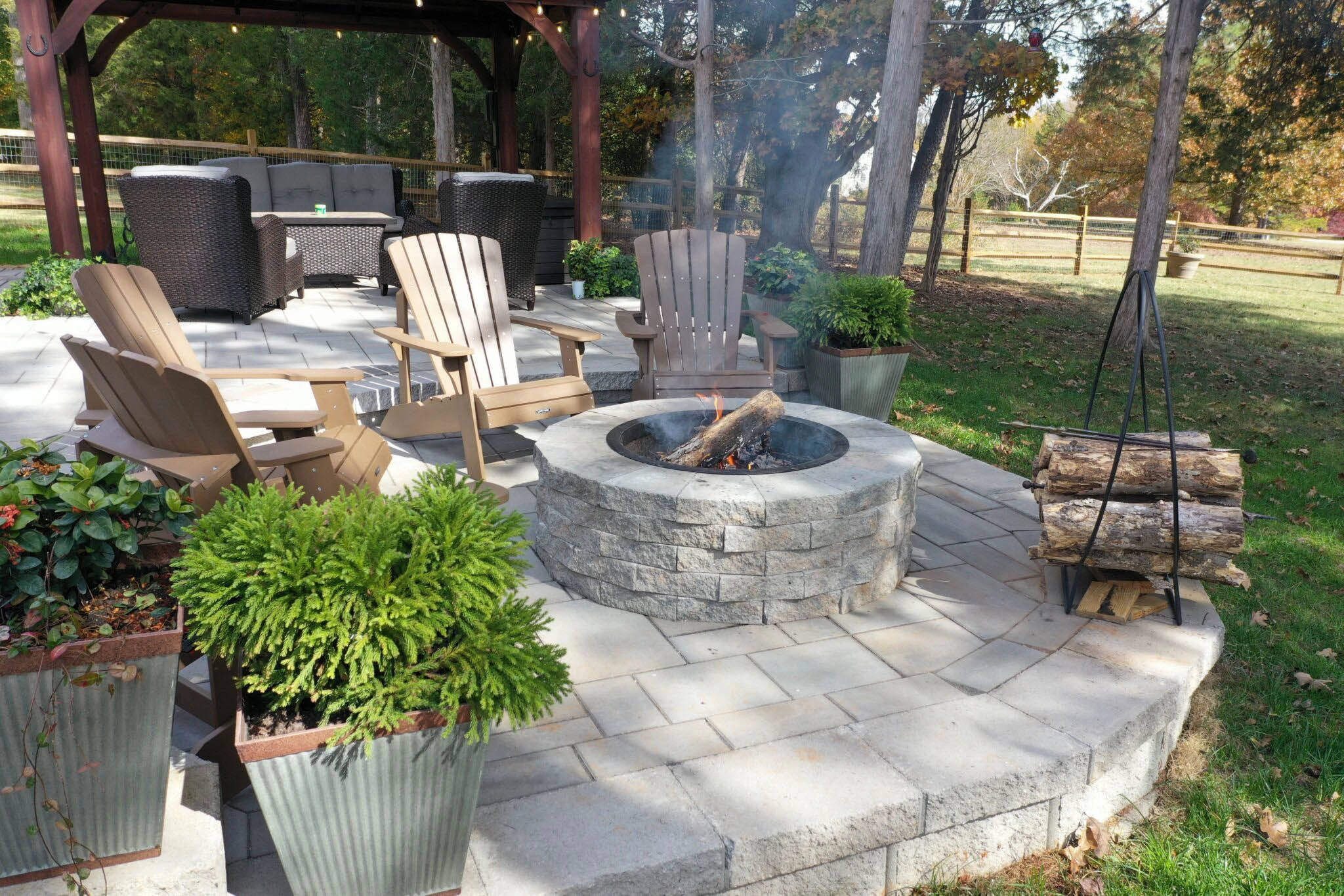 Circular stone gas fire pit surrounded by pavers on a flat Forsyth County backyard patio — Forsyth County, GA