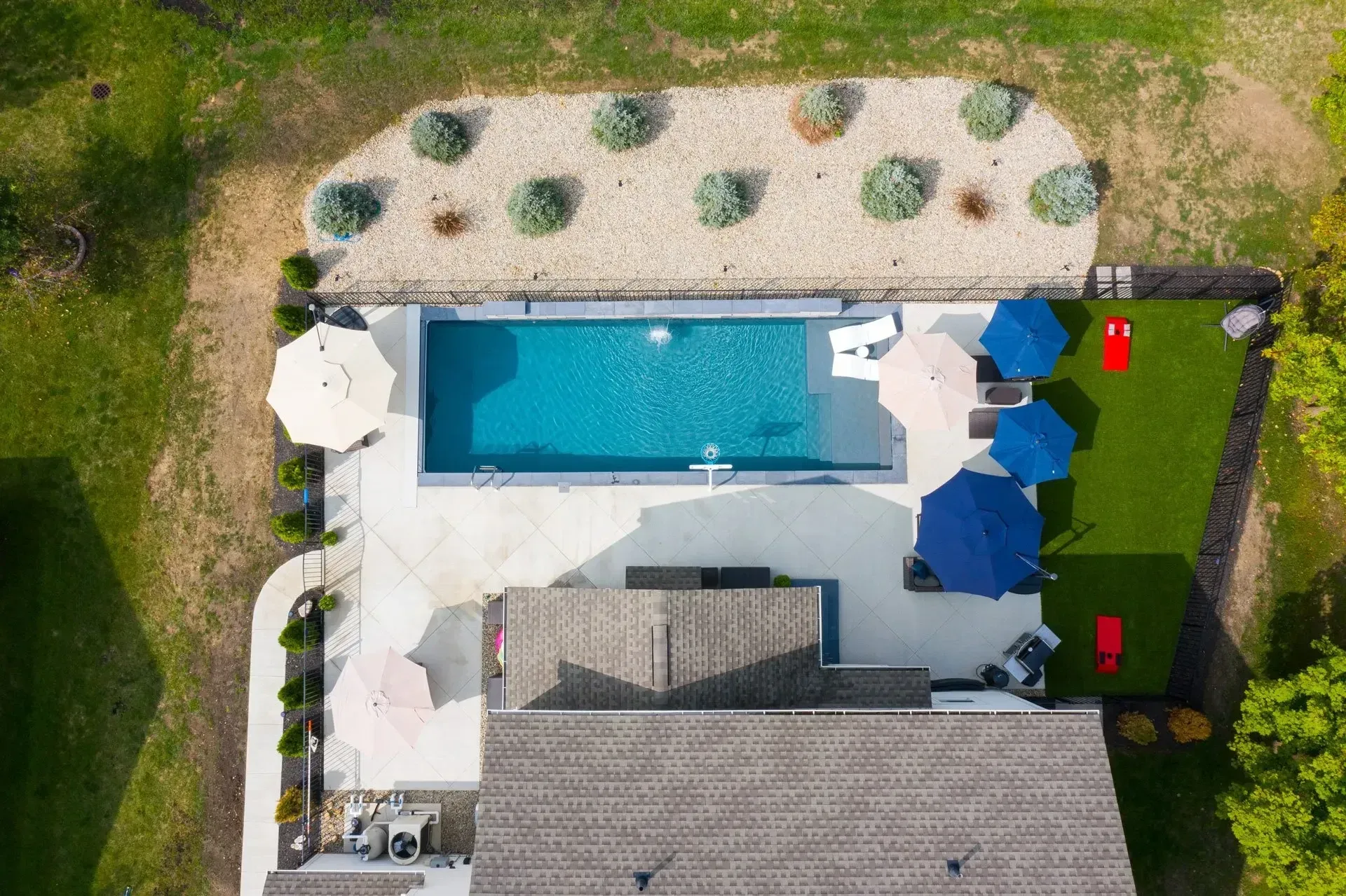 Aerial top-down view of rectangular Cumming pool with curved tanning ledge and gray concrete-feel deck, Cumming GA