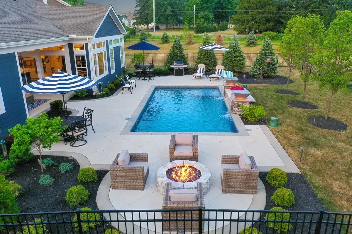 Aerial of Marietta backyard with rectangular pool, concrete deck, and detached circular paver fire pit patio