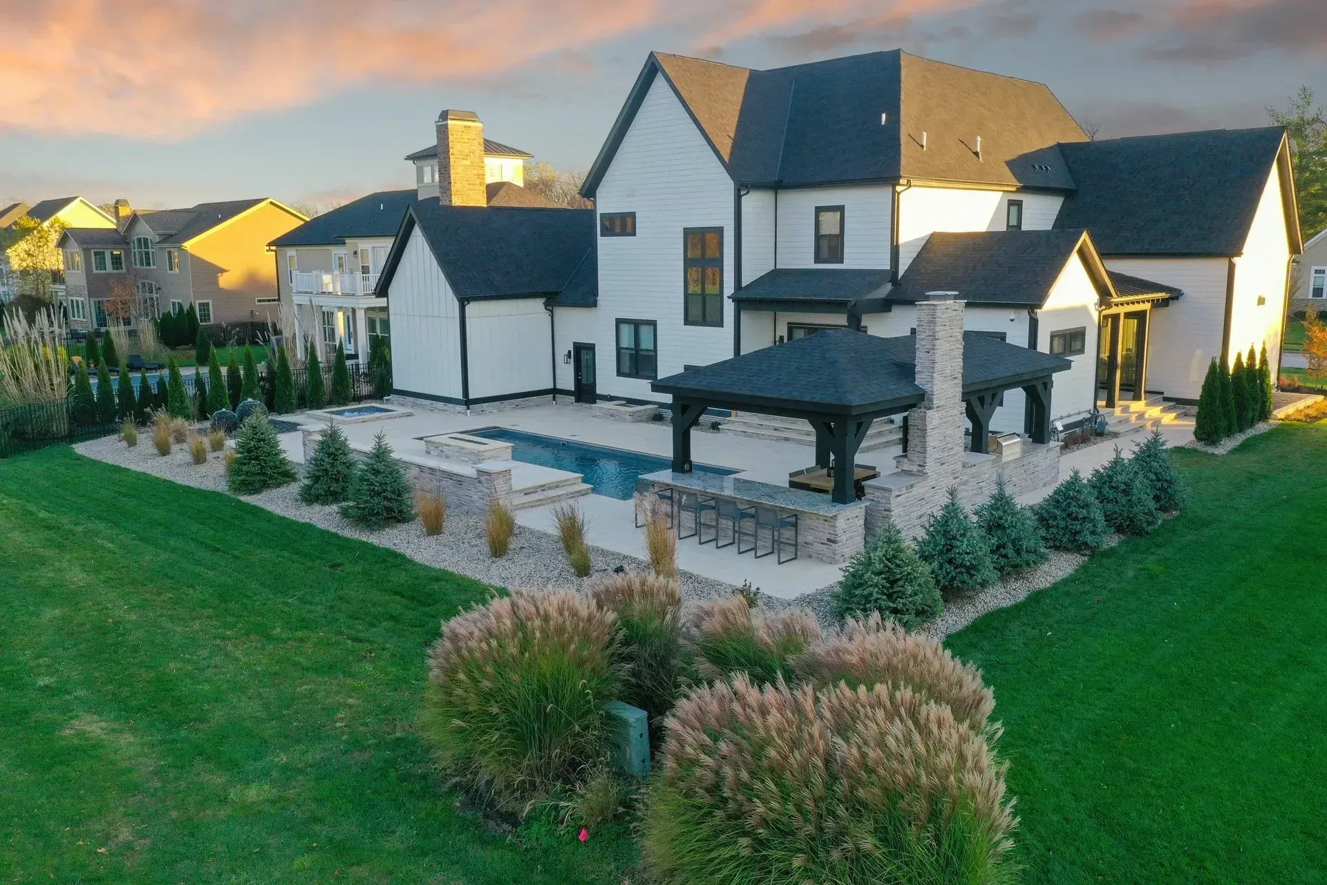 Aerial luxury backyard with rectangular pool, raised spa, sunken fire pit, pavilion and cream deck in Suwanee, GA