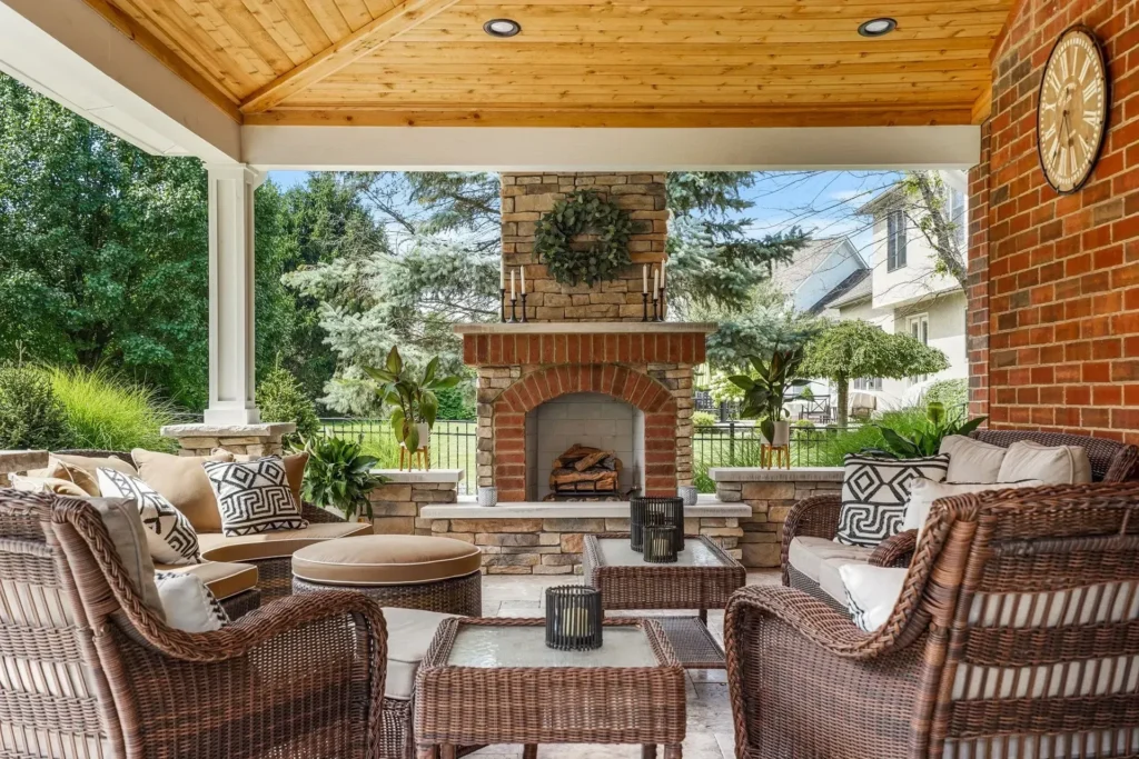 Covered porch with cedar T&G ceiling, brick FIREPLACE with cedar mantel and wreath, wicker seating room — backyard pergola in Milton, GA by Primetime Pools.